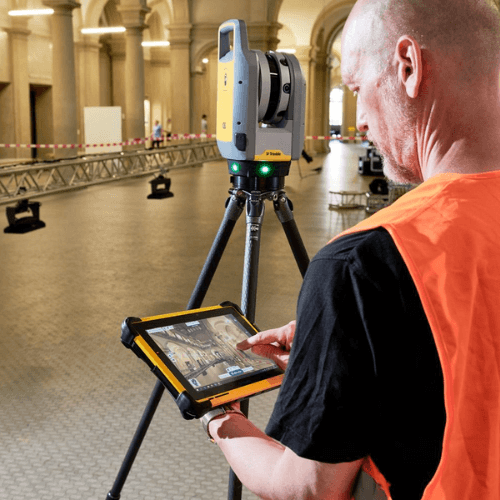 Técnico escaneando una estructura con escáner en tripié y tableta
